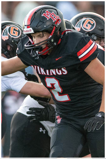 A football player wearing a black jersey with the number 2 on it. Description generated by AI