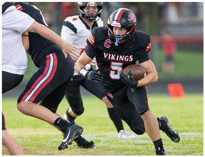 A football player running with the number 5 on his jersey. Description generated by AI