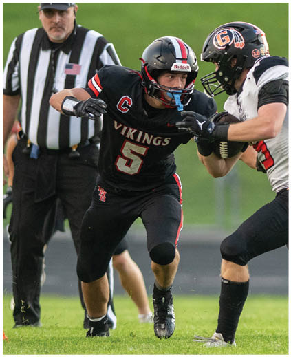 A football player wearing a black jersey with the number 5 on it. Description generated by AI