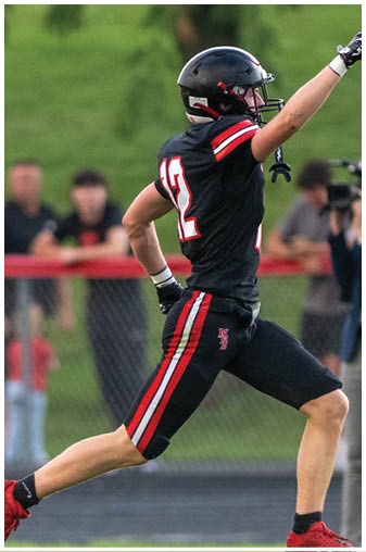 A man wearing a football jersey with the number 19 running on the field. Description generated by AI