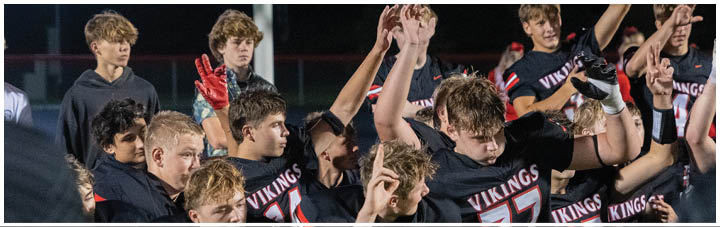 A group of young men wearing black jerseys with the word Vikings on them. Description generated by AI