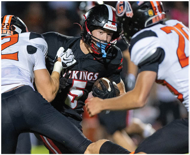A football player wearing a black jersey with the number 5 on it. Description generated by AI