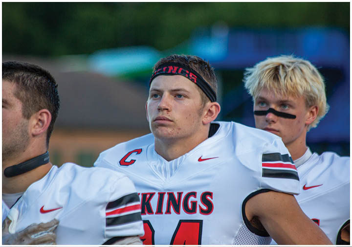 Three football players wearing white jerseys with the word “Kings" on the front. Description generated by AI