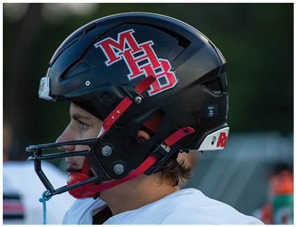 A football player wearing a helmet with the letters MH on it. Description generated by AI