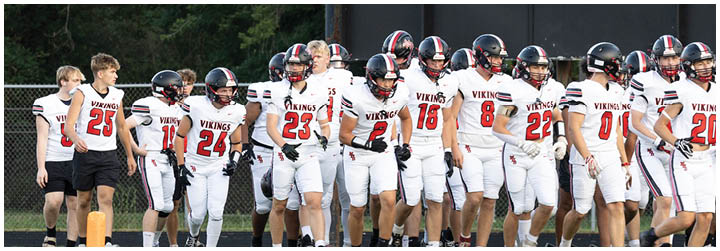 A group of football players wearing white and black uniforms. Description generated by AI