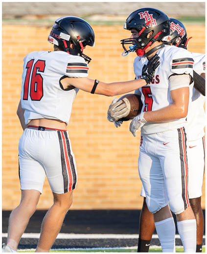 Two football players wearing white uniforms with red numbers and black helmets. Description generated by AI