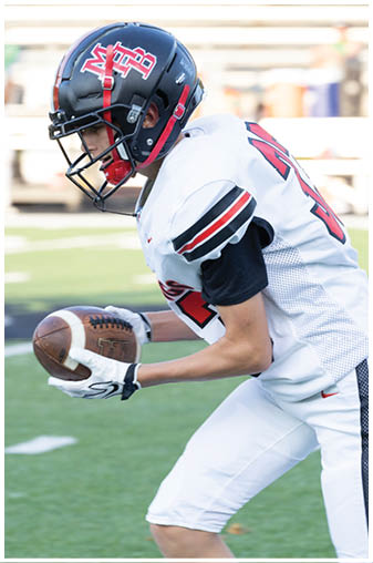 A football player wearing a helmet and white uniform is holding a football. Description generated by AI