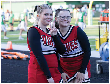 Two cheerleaders in red and white uniforms. Description generated by AI
