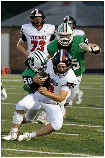 A football player in a white jersey is tackled by another player. Description generated by AI
