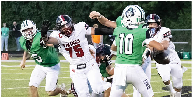 A football player in a green jersey is tackled by another player. Description generated by AI