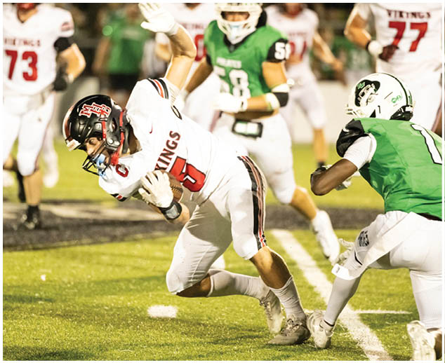 A football player in a green jersey is tackling another player. Description generated by AI