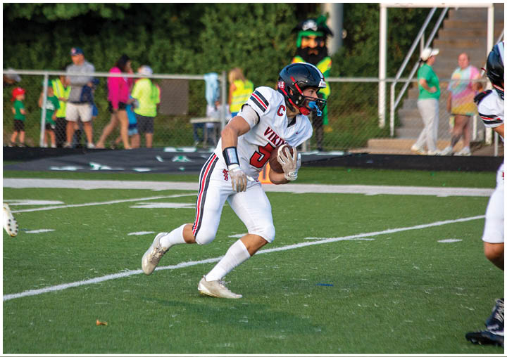 A football player in a white uniform running with a football. Description generated by AI