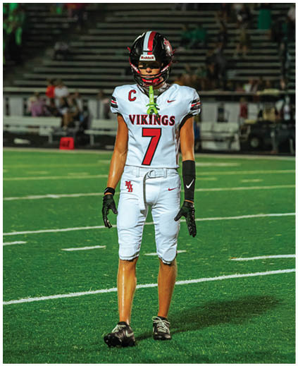 A football player wearing a white jersey with the number 7 on it. Description generated by AI
