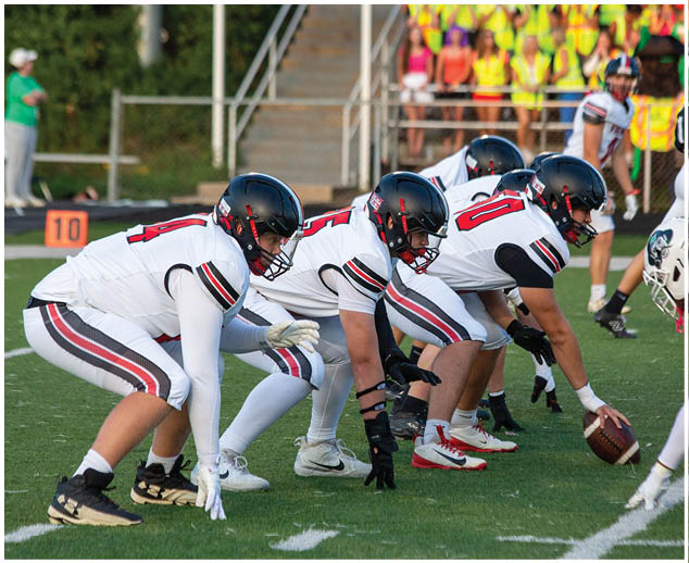 A group of football players in white and black uniforms are on the field. Description generated by AI