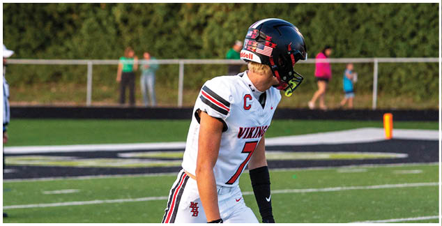 A football player wearing a white and black uniform. Description generated by AI