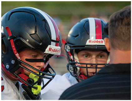 A group of football players wearing helmets. Description generated by AI