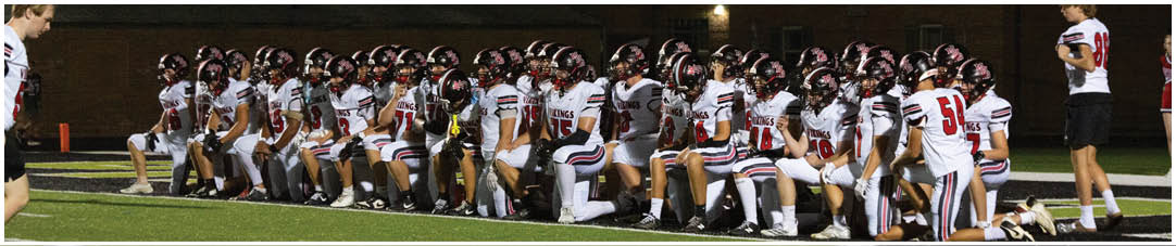 A group of football players kneeling on the field. Description generated by AI