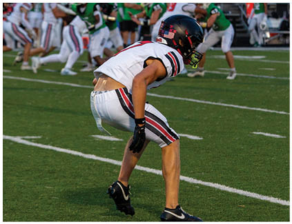 A football player is bent over on the field. Description generated by AI