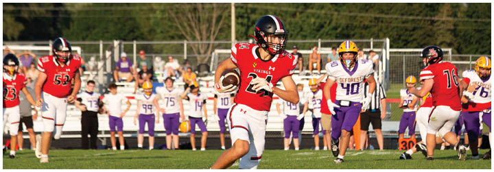 A football player in a red jersey is running with the ball. Description generated by AI