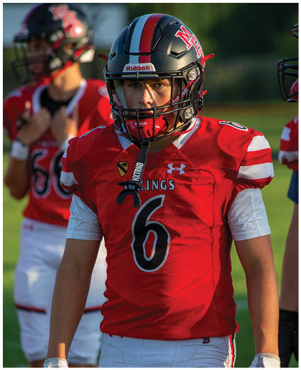 A football player wearing a red jersey with the number 6 on it. Description generated by AI
