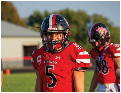 A football player wearing a red jersey with the number 5 on it. Description generated by AI
