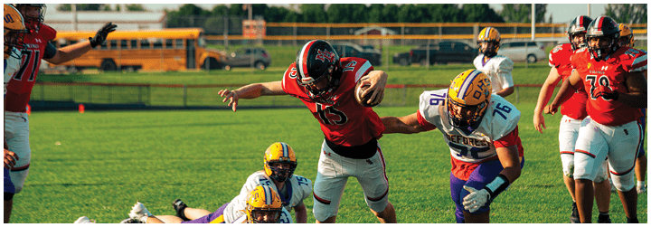 A football player in a red jersey is about to kick the ball. Description generated by AI