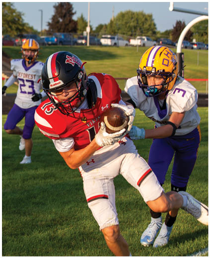 A football player in a red jersey is trying to catch a football. Description generated by AI