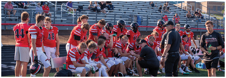 A group of football players sitting on the ground. Description generated by AI