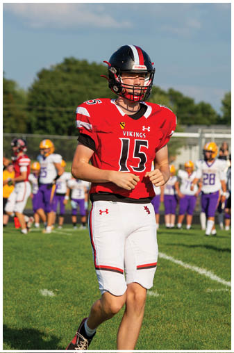 A football player wearing a red jersey with the number 15. Description generated by AI