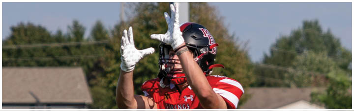 A man wearing a red jersey with the number 88 catching a football. Description generated by AI