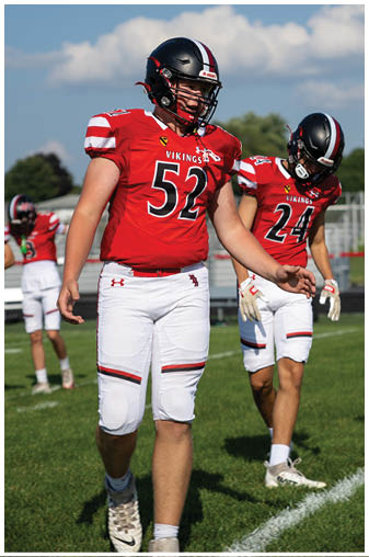 Two football players wearing red and white uniforms. Description generated by AI