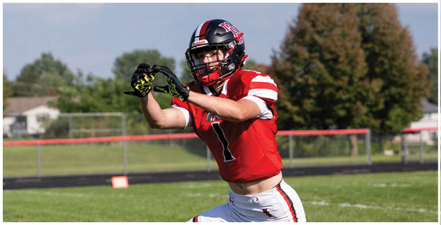 A man in a red jersey catches a football. Description generated by AI