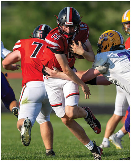 A football player in a red jersey is tackled by another player. Description generated by AI