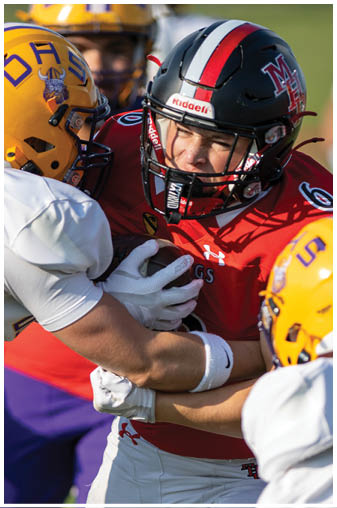 A football player wearing a red jersey is tackled by another player. Description generated by AI