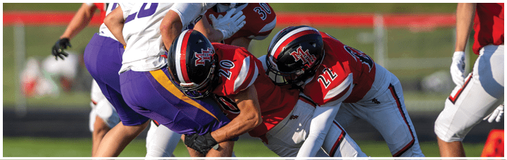 A football player in a red jersey is tackled by two other players. Description generated by AI