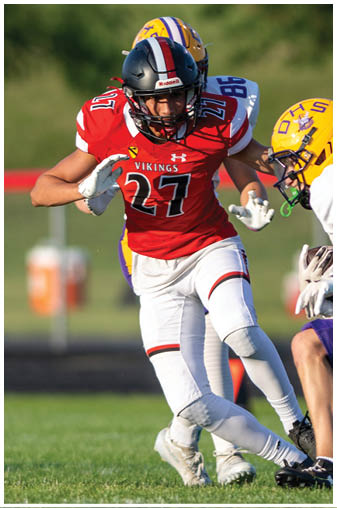 A football player in a red jersey is running with the ball. Description generated by AI