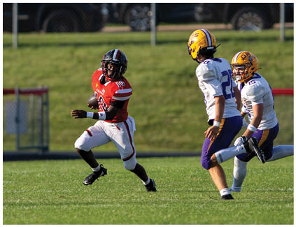 A football player in a red jersey running with the ball. Description generated by AI