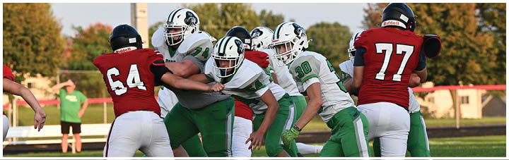 A football player in a green jersey is tackled by another player. Description generated by AI