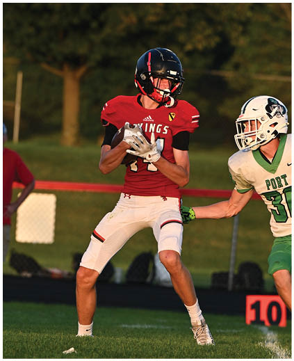 A football player in a red jersey catching a ball. Description generated by AI