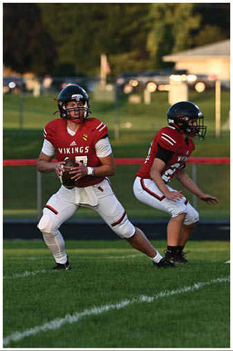 A football player in a red jersey is running with the ball. Description generated by AI