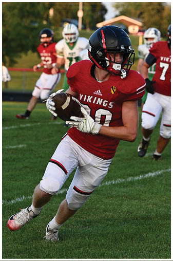A football player in a red jersey is running with a football. Description generated by AI