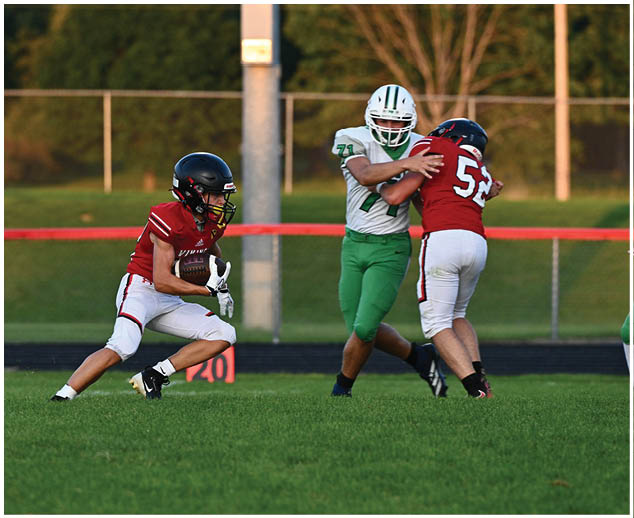A football player in a red jersey is tackling another player. Description generated by AI