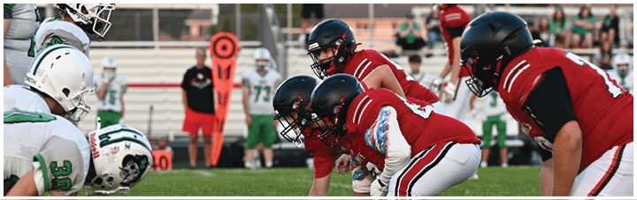 A group of football players in red and green uniforms on a field. Description generated by AI