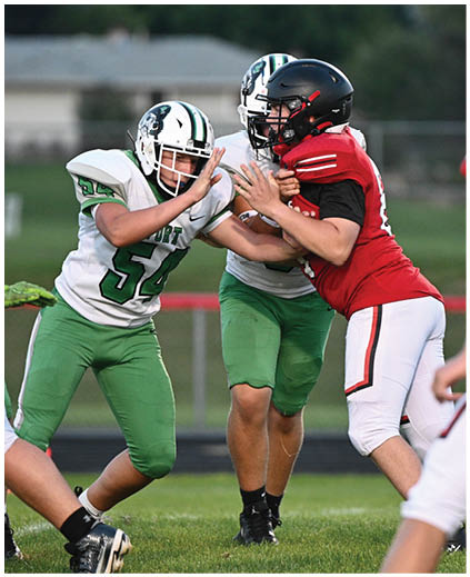 A football player in a green jersey is tackling another player. Description generated by AI