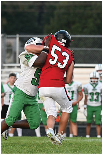 A football game is being played with a man in a red jersey running with the ball. Description generated by AI