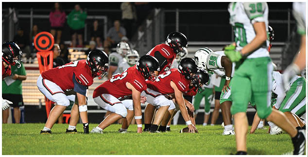 A group of football players in red and green uniforms are on the field. Description generated by AI