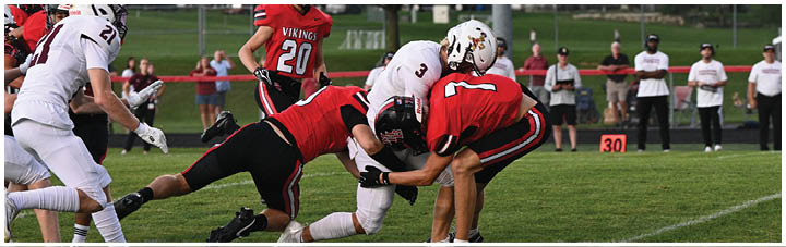 A football player in a red jersey is tackled by another player. Description generated by AI