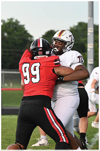 Two football players in red and white uniforms are fighting for the ball. Description generated by AI
