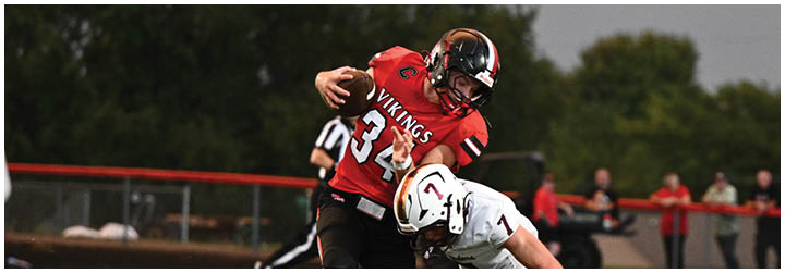 A football player in a red jersey tackles another player in a white jersey. Description generated by AI