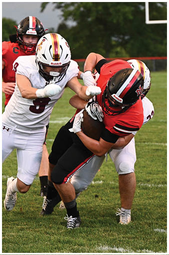 A football player in a red jersey is tackled by another player. Description generated by AI